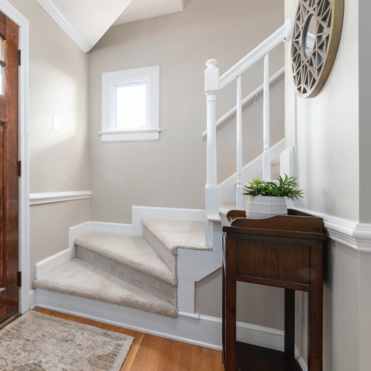 Paredes de la entrada de la casa y escaleras de color lino combinado con blanco
