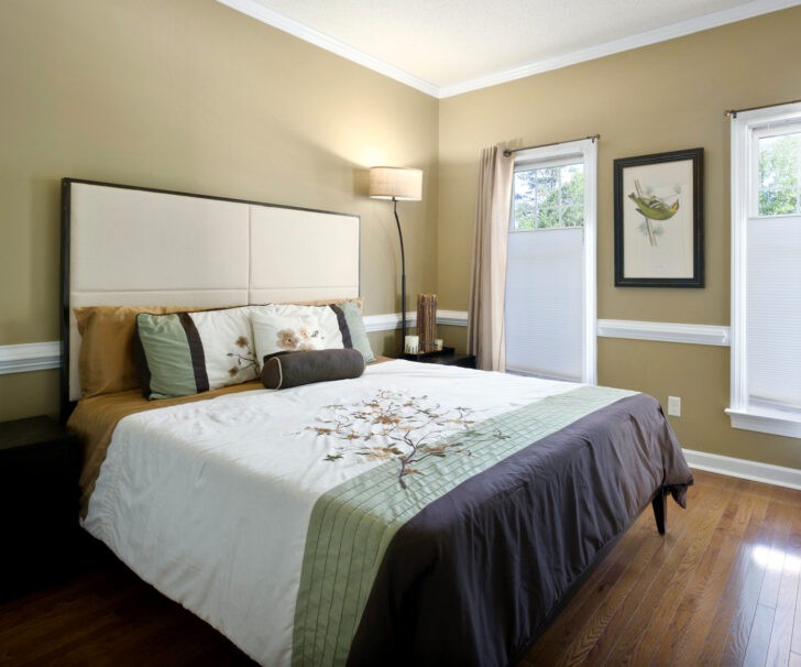 Dormitorio con paredes en color beige, cama en blanco y café