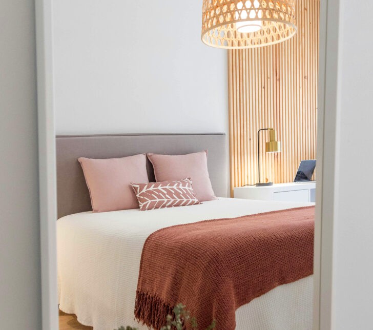 Cuarto dormitorio con paredes blancas y almohadones rosados