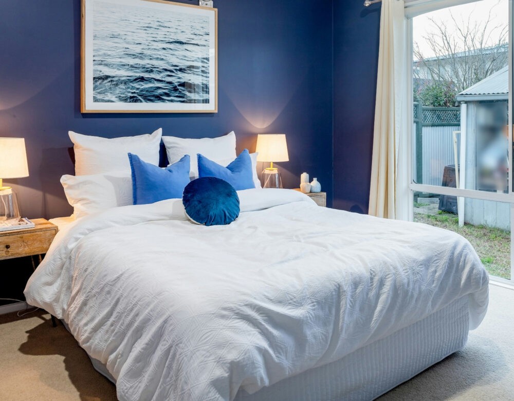 Dormitorio con paredes azul intenso y cama de color blanco