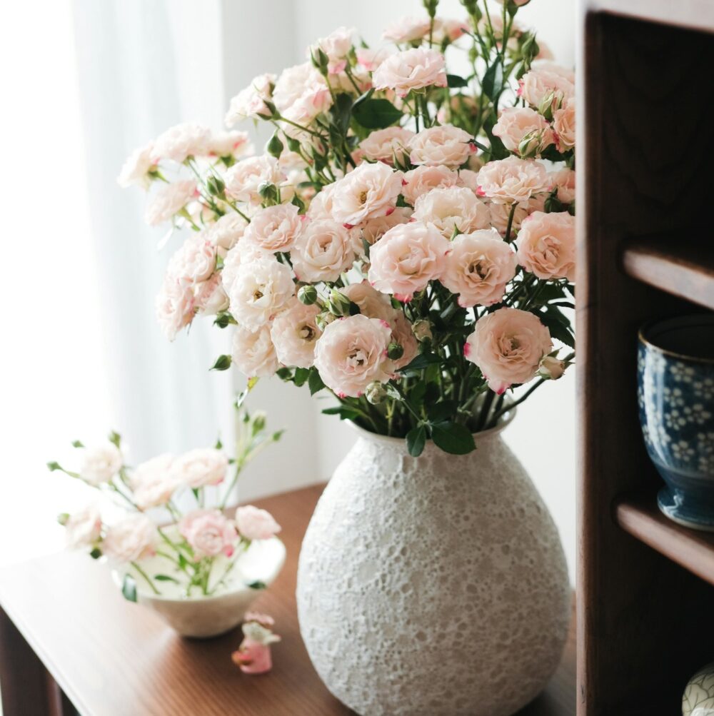 Ramo de flores rosadas en un jarrón junto a la ventana