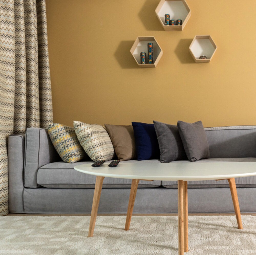 Paredes del salón de color ocre y sofá gris ceniza