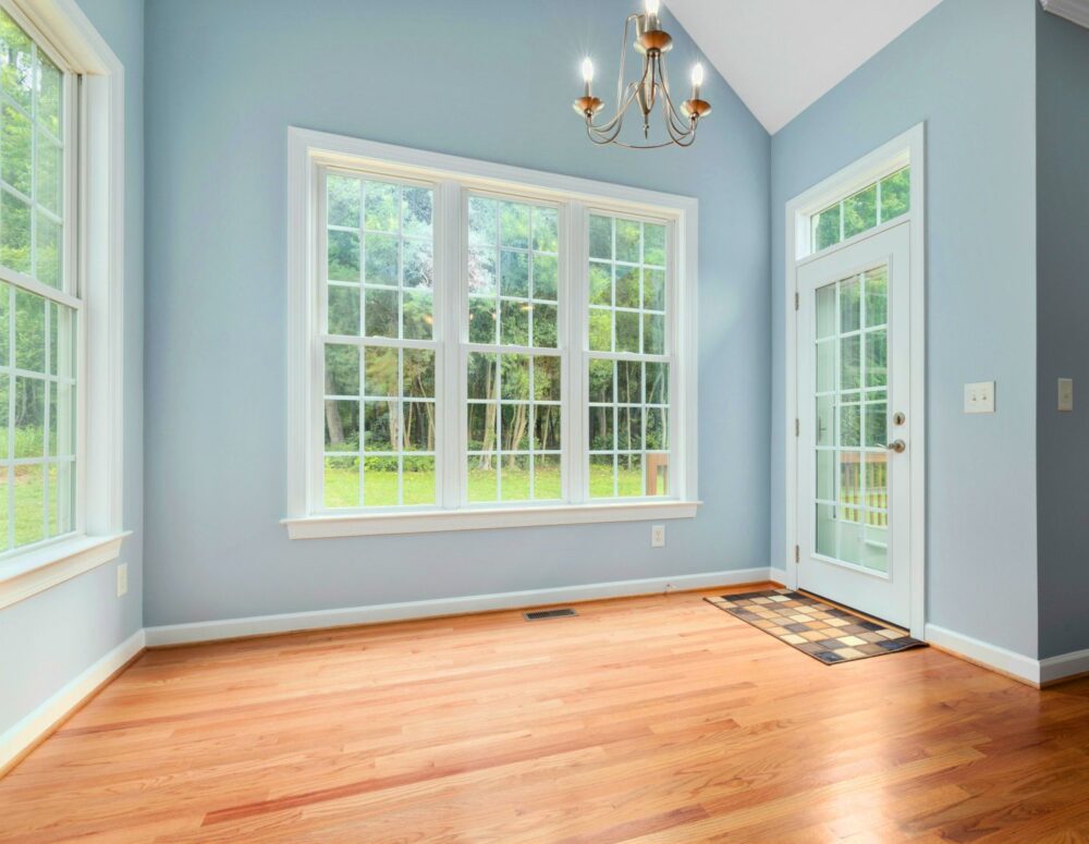Interior con las paredes pintadas de azul glaciar, ventanas blancas y suelo de madera
