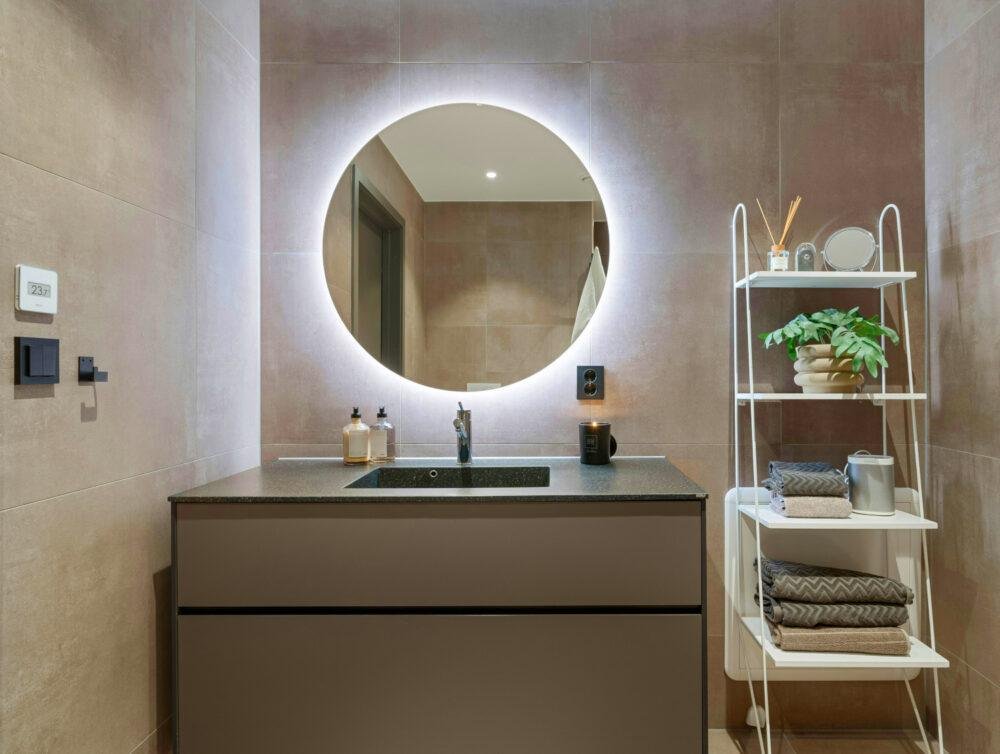 Baño moderno con espejo redondo retroiluminado