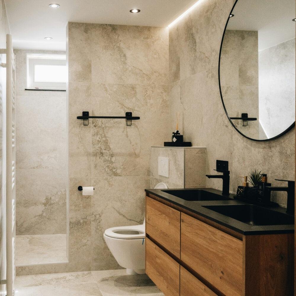Baño en tonos arena con mueble flotante de madera y encimera negra