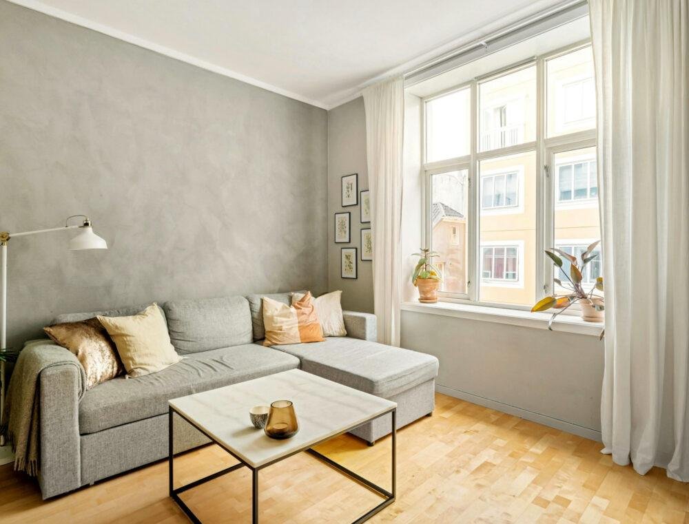 Salón sencillo y luminoso con paredes gris claro y suelo de madera