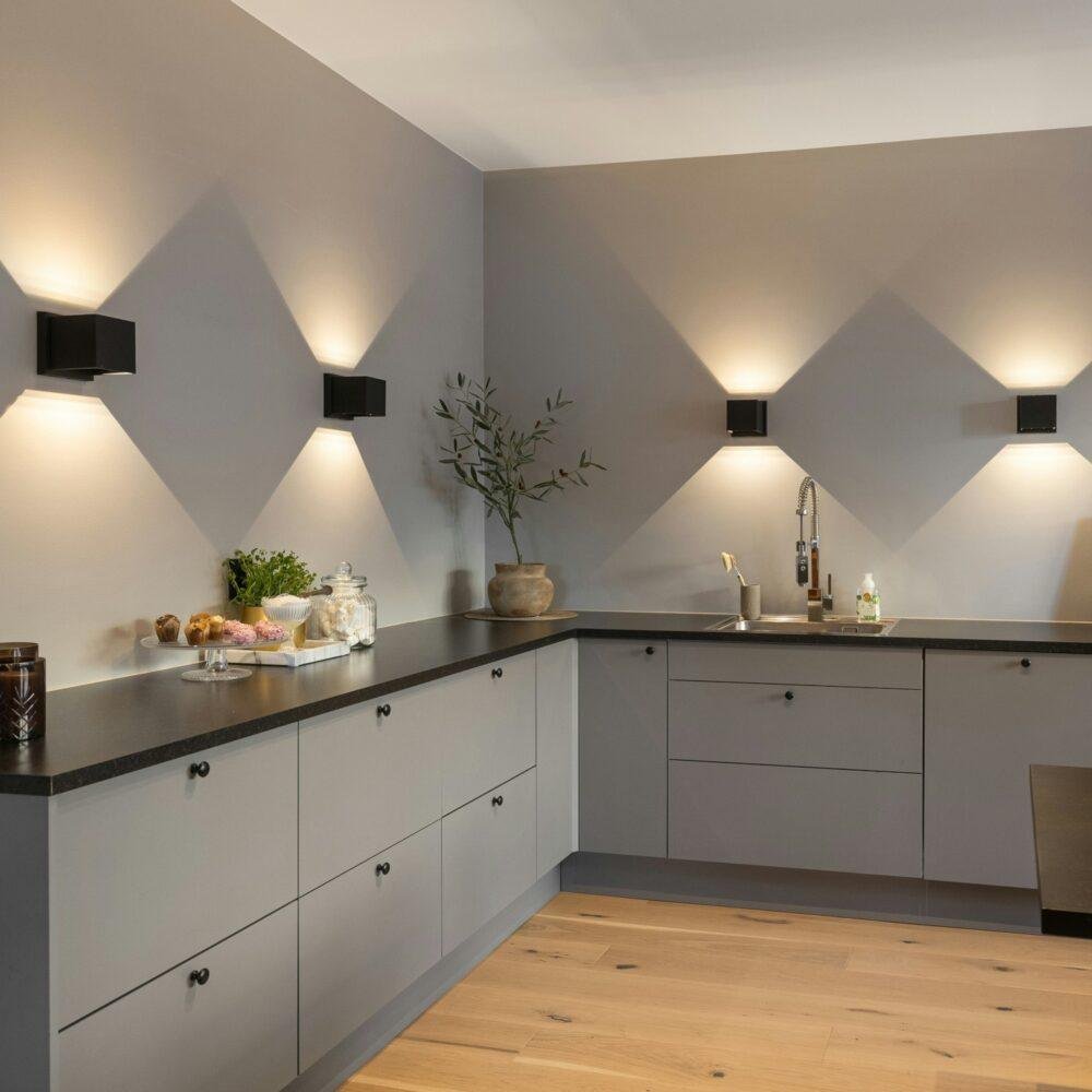 Una cocina elegante con muebles y paredes en gris humo, encimera negra y luces o apliques bidireccionales