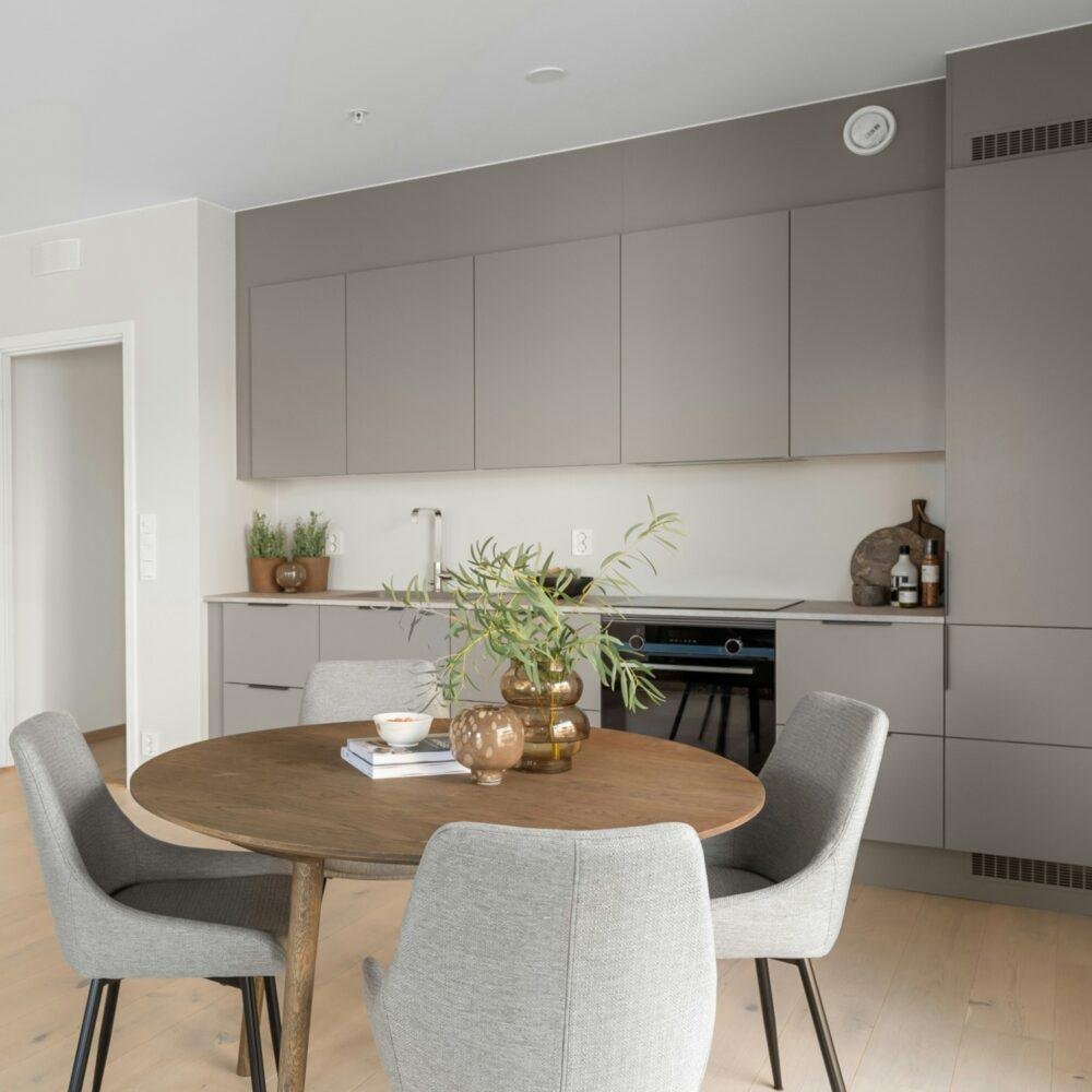 Cocina de muebles grises y paredes blancas junto a una mesa redonda