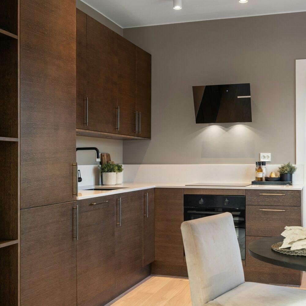 Cocina con muebles de madera oscura, paredes grises y encimera de color blanco