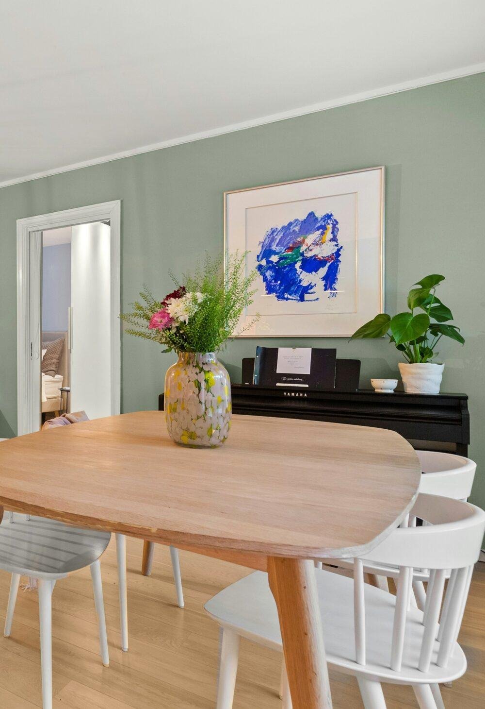 Paredes de un comedor en eucalipto con mesa de madera y sillas blancas
