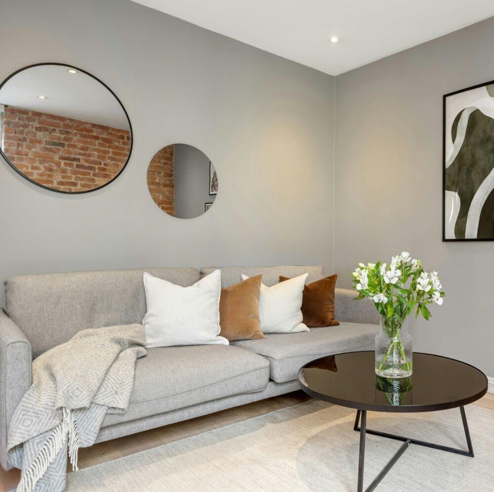 Paredes de un salón gris ceniza, sofá gris y elementos decorativos