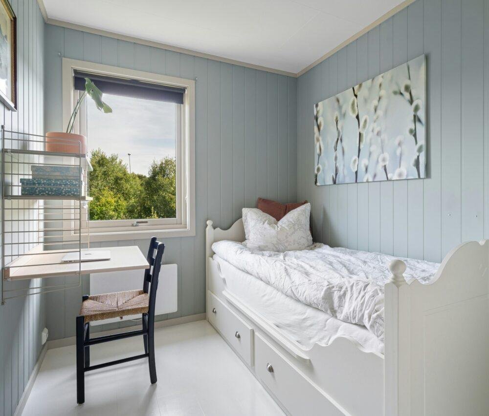 Dormitorio pequeño con cama de una plaza blanca y paredes de color gris azulado claro