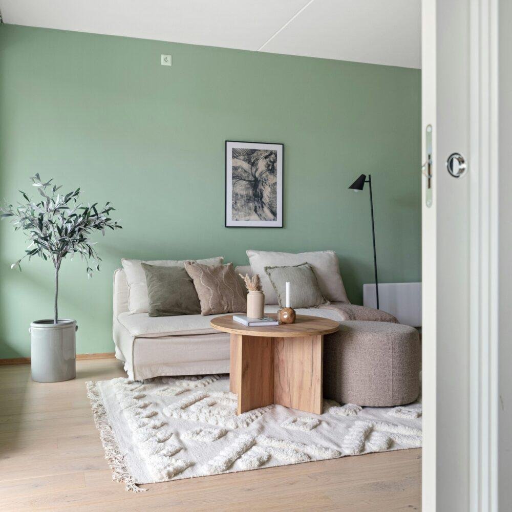 Salón con paredes pintadas en verde meta, muebles y detalles en grises suaves y maderas claras